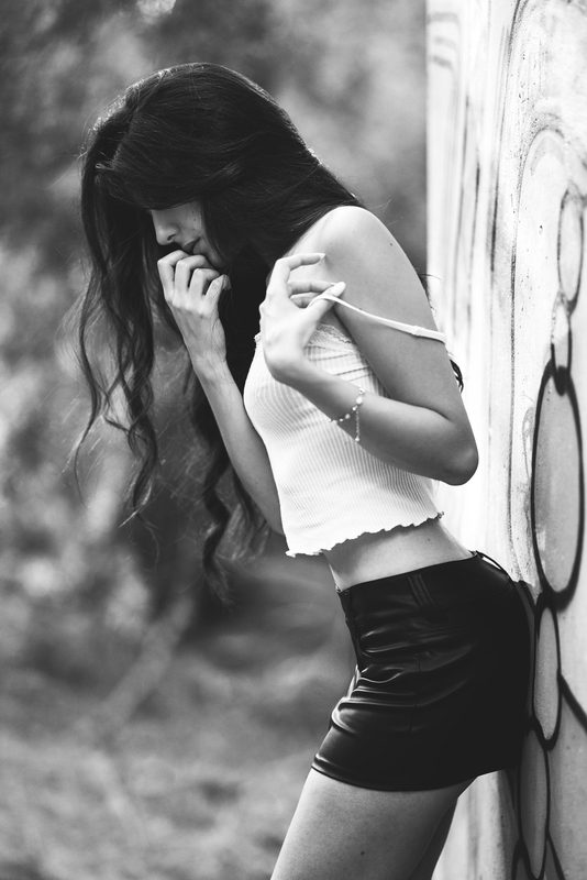 Ritratto in bianco e nero di una donna appoggiata a un muro con graffiti