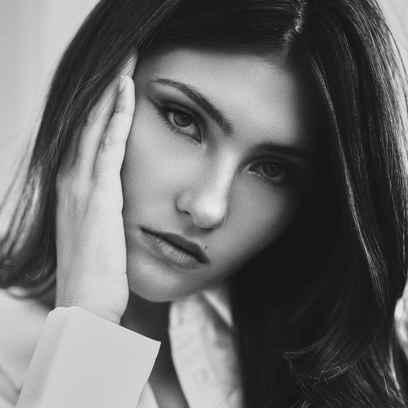Ritratto in bianco e nero di una donna con la mano sul viso, luce naturale morbida