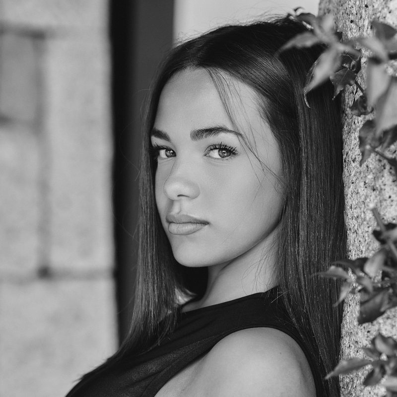 Ritratto in bianco e nero di una donna davanti a un muro di pietra con l'edera, Alghero