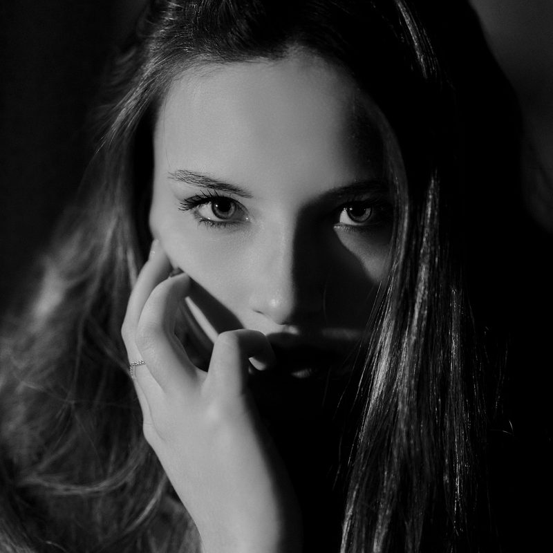 Ritratto in bianco e nero di una donna in penombra, la mano appoggiata alla guancia