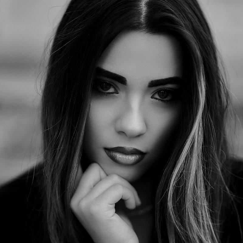 Ritratto in bianco e nero di una donna con la mano al mento e le labbra scure