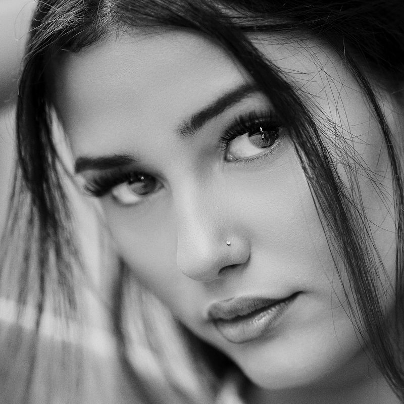 Primo piano in bianco e nero di una donna con lo sguardo diretto, luce naturale