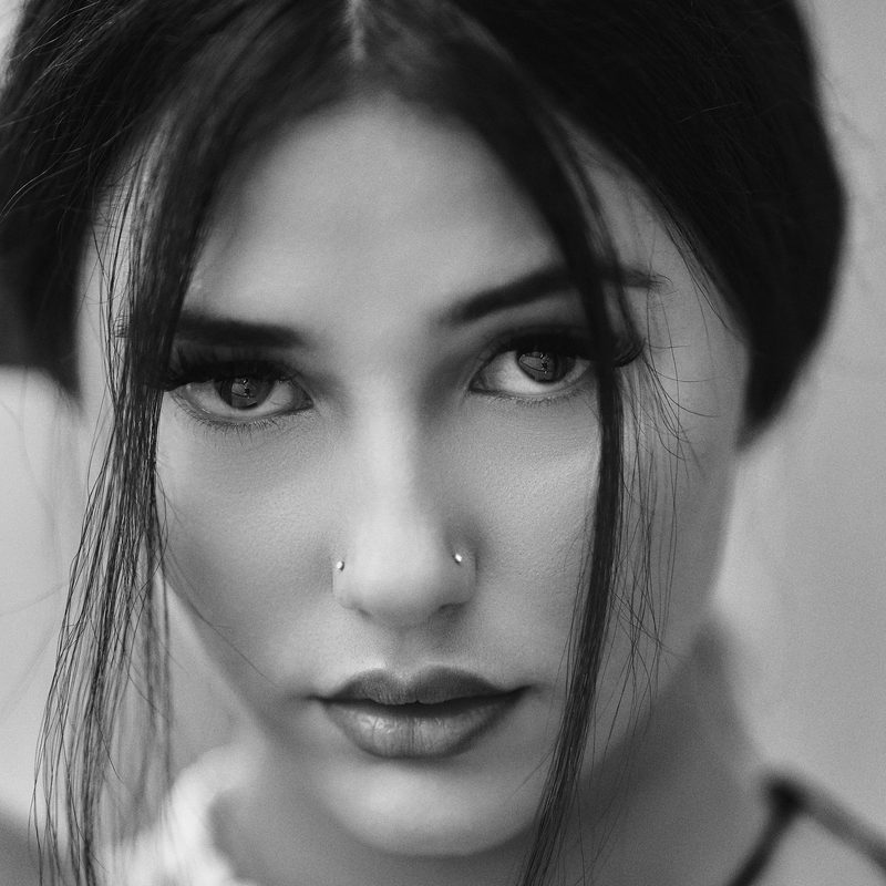 Primo piano in bianco e nero di una donna con il piercing al naso e lo sguardo frontale