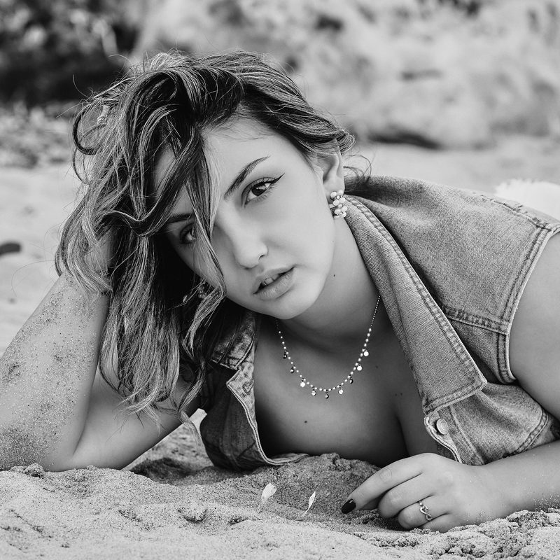 Ritratto in bianco e nero di una donna sdraiata sulla sabbia, in riva al mare