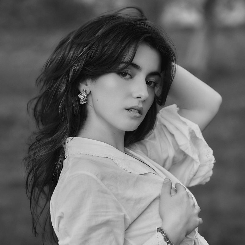 Ritratto in bianco e nero di una donna in camicia bianca, luce naturale in esterno
