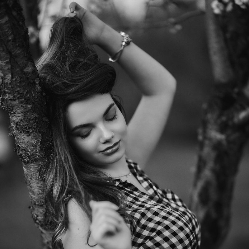 Ritratto in bianco e nero di una donna appoggiata a un albero, gli occhi chiusi
