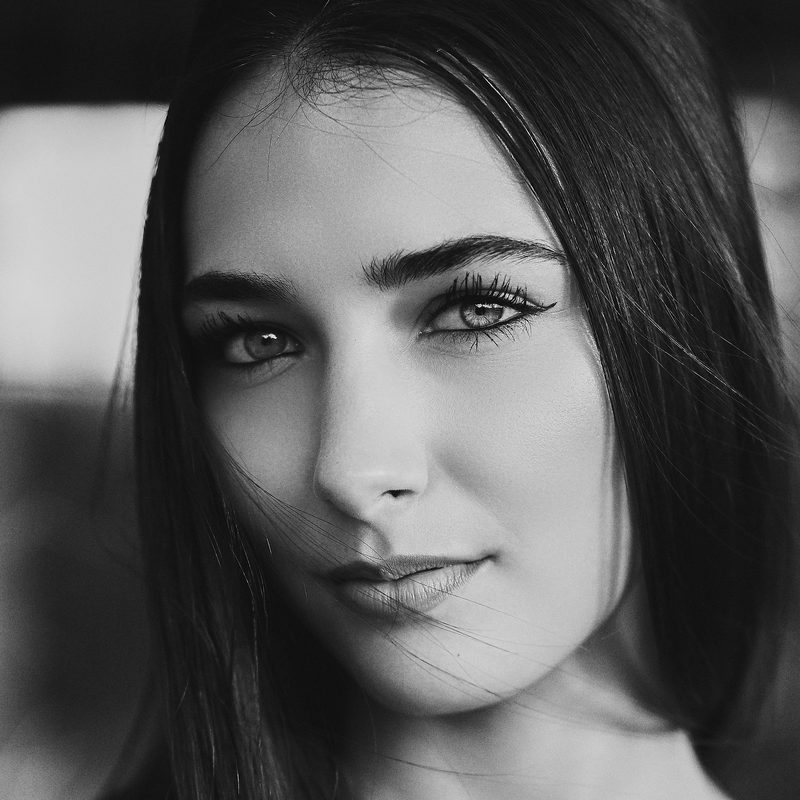Ritratto in bianco e nero di una donna con le braccia sollevate sopra la testa, in un porticato