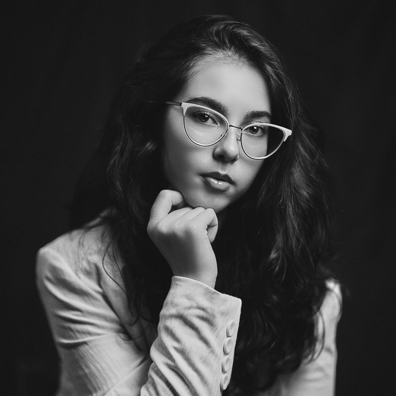 Ritratto in bianco e nero di una donna in camicia bianca davanti a una porta di legno