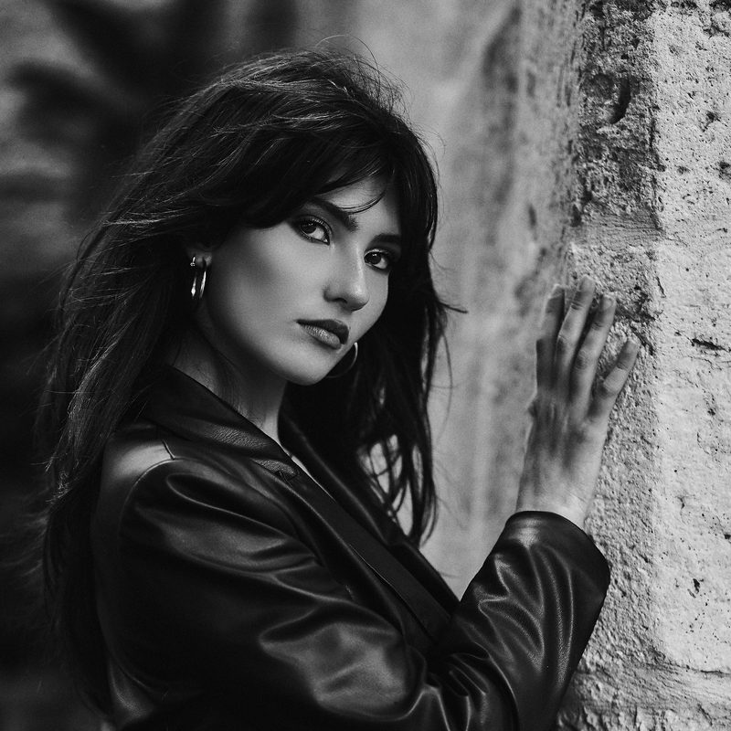 Ritratto in bianco e nero di una donna in giacca di pelle, la mano tra i capelli