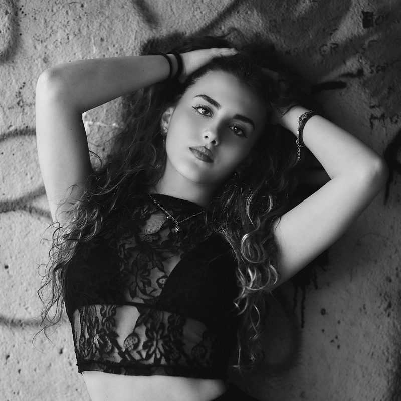 Ritratto in bianco e nero di una donna con i capelli raccolti e un abito di pizzo, la mano al viso
