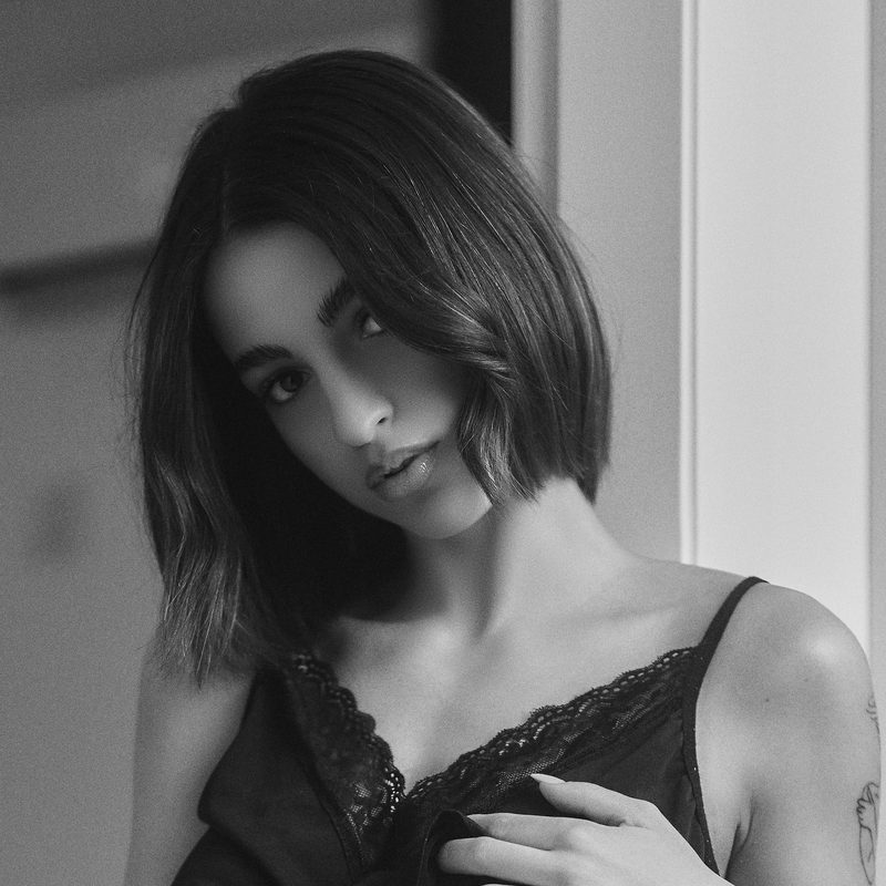 Primo piano in bianco e nero di una donna con la mano alle labbra e i capelli mossi dal vento