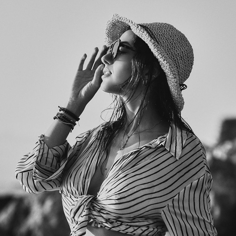Ritratto in bianco e nero di una donna di spalle, davanti ai pini e al mare